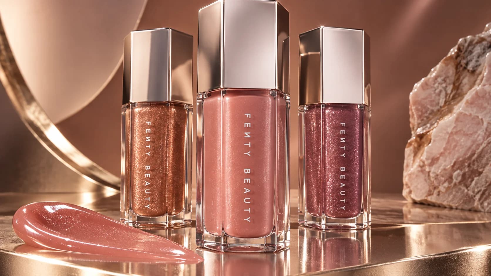 Fenty Beauty gloss trio on a bronze podium